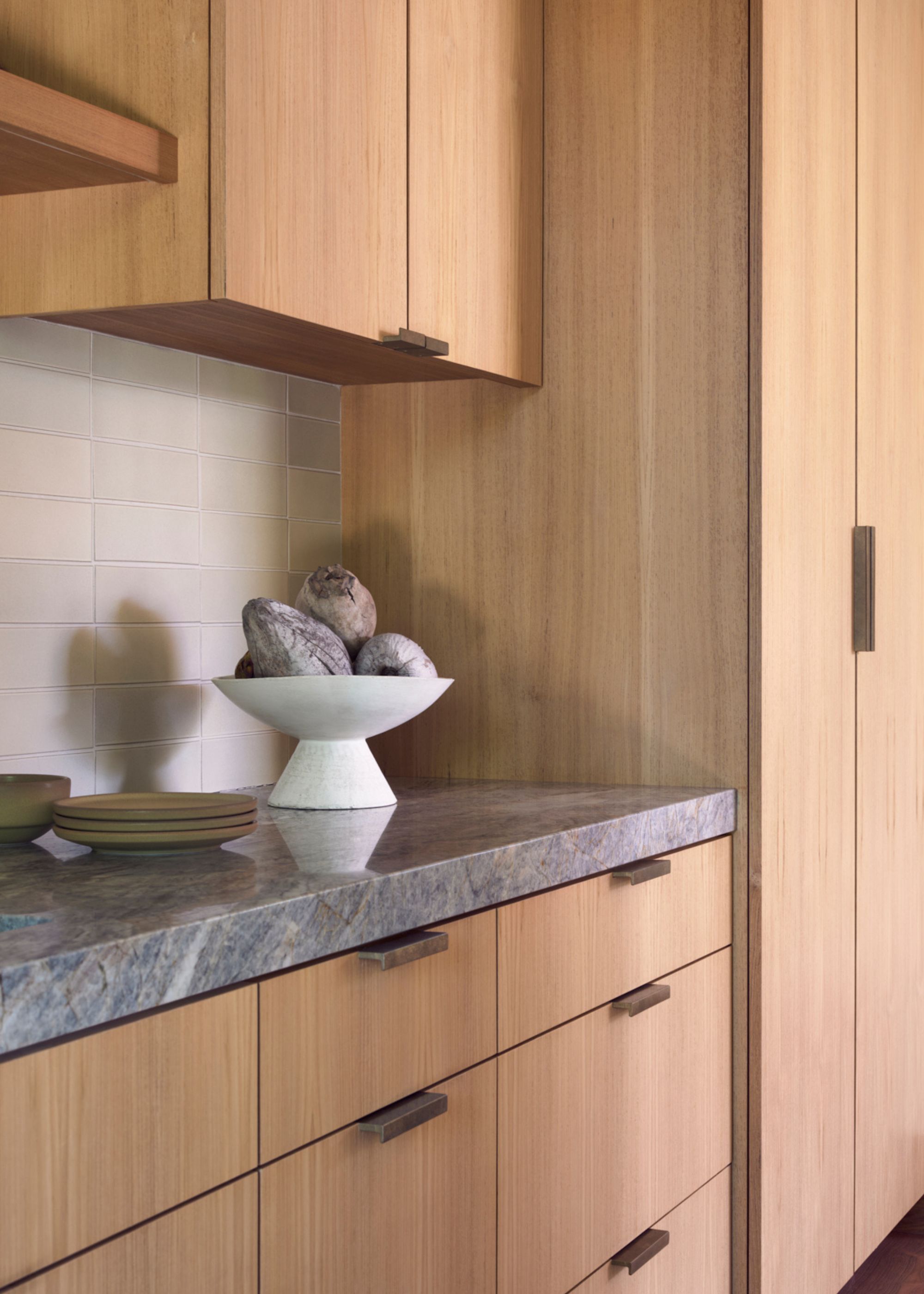 a kitchen with granite worktops. On the counter is a bowl of fruit and a few plates