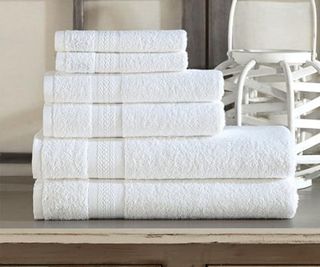 Stack of Wamsutta towels on a wooden dresser.