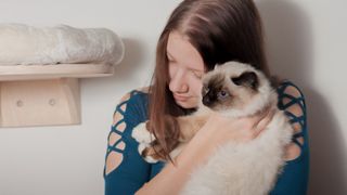 Woman cuddling birman cat