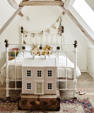 childrens attic bedroom with iron bed and doll's house