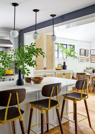 kitchen with dark wood bar stools and modern oval lights above an island