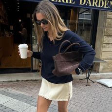 fashion collage featuring style influencer Anne-Laure Mais wearing a fall 2025 outfit idea with a navy blue sweater, brown suede bag, and beige silk skirt with lace trim