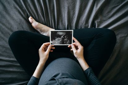Pregnant woman holding ultrasound photo.