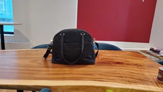 a black overnight bag sitting on a wooden desk
