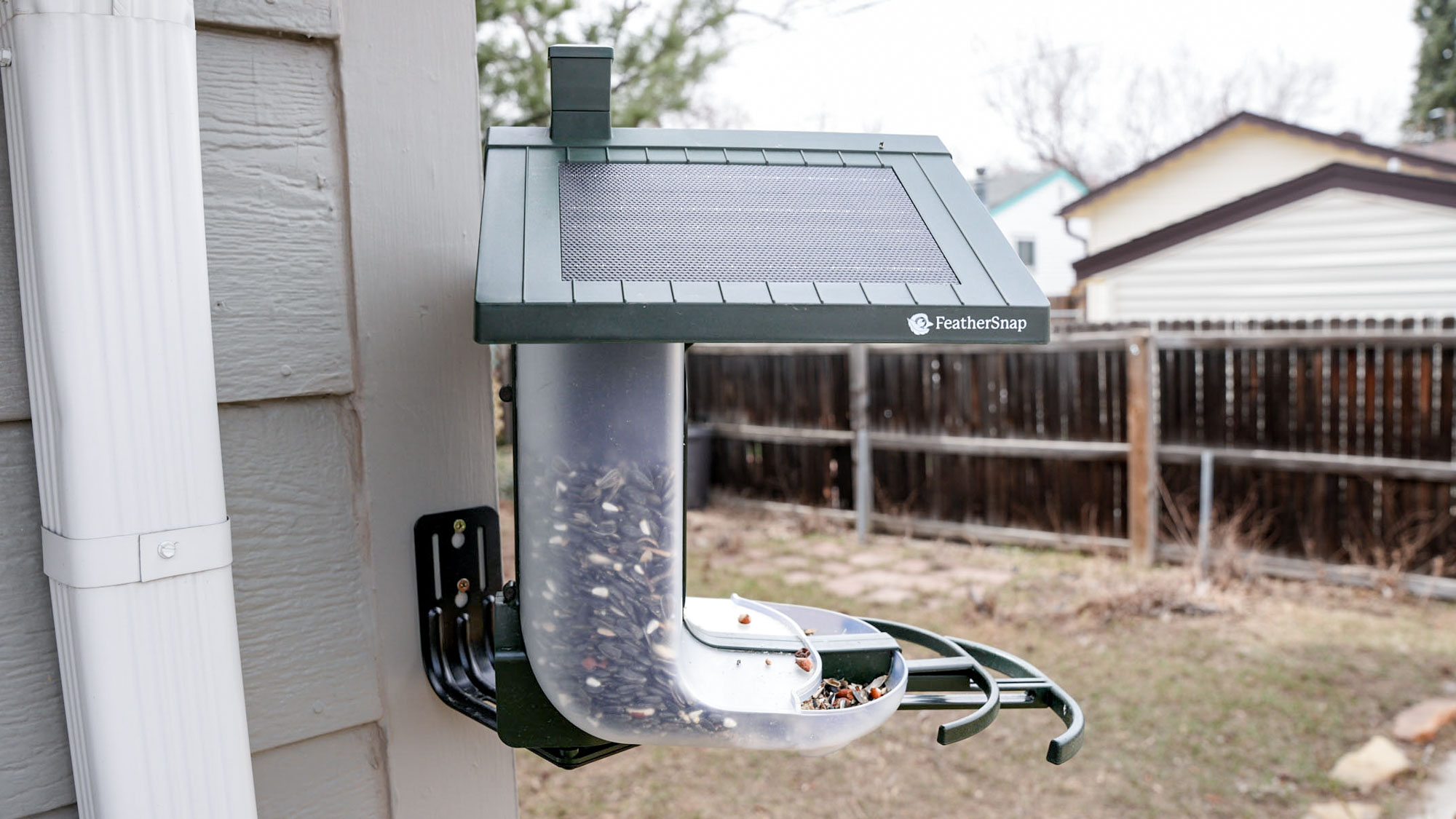 Side view of the Feathersnap Scout Bird Feeder mounted on the side of a house.