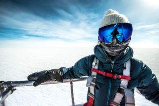 a person in protective gear poses for a portrait among a barren landscape of snow