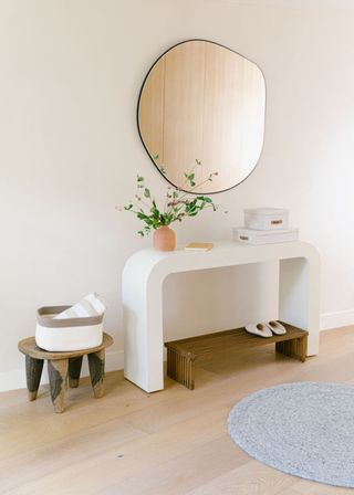 An entryway with a side table and a stool for shoes