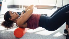 mixed race female stretching her back on an orange foam roller