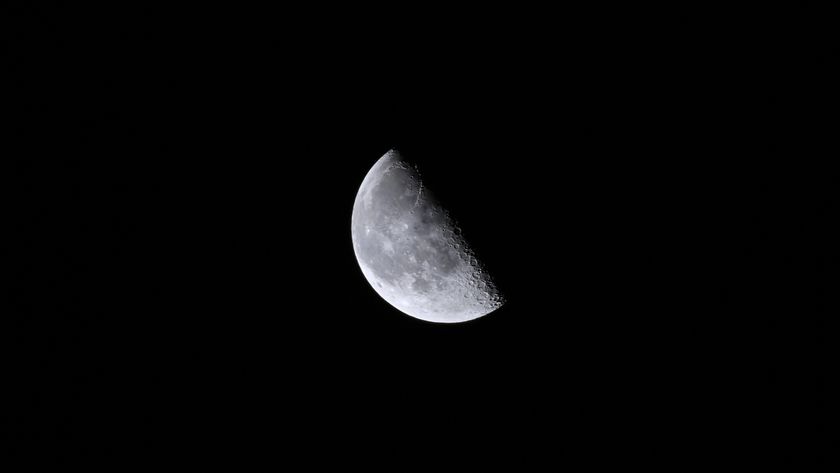 A close up of the moon in the darkness of space, with its top right half obscured in shadow