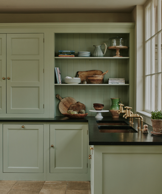 Sage green kitchen with wooden floors and open shelving