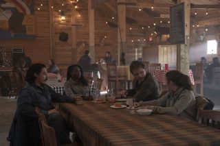 A group of people (Gabriel Luna, Rutina Wesley, Pedro Pascal, Bella Ramsey) sit around a dining table, in 'The Last of Us' season 1.