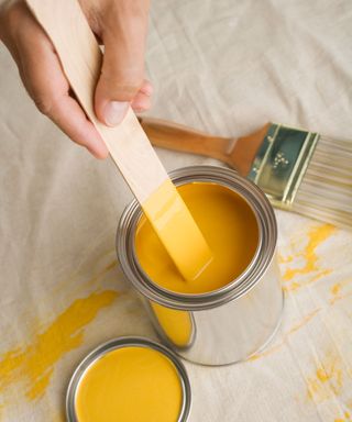 yellow paint tin with mixer and brush