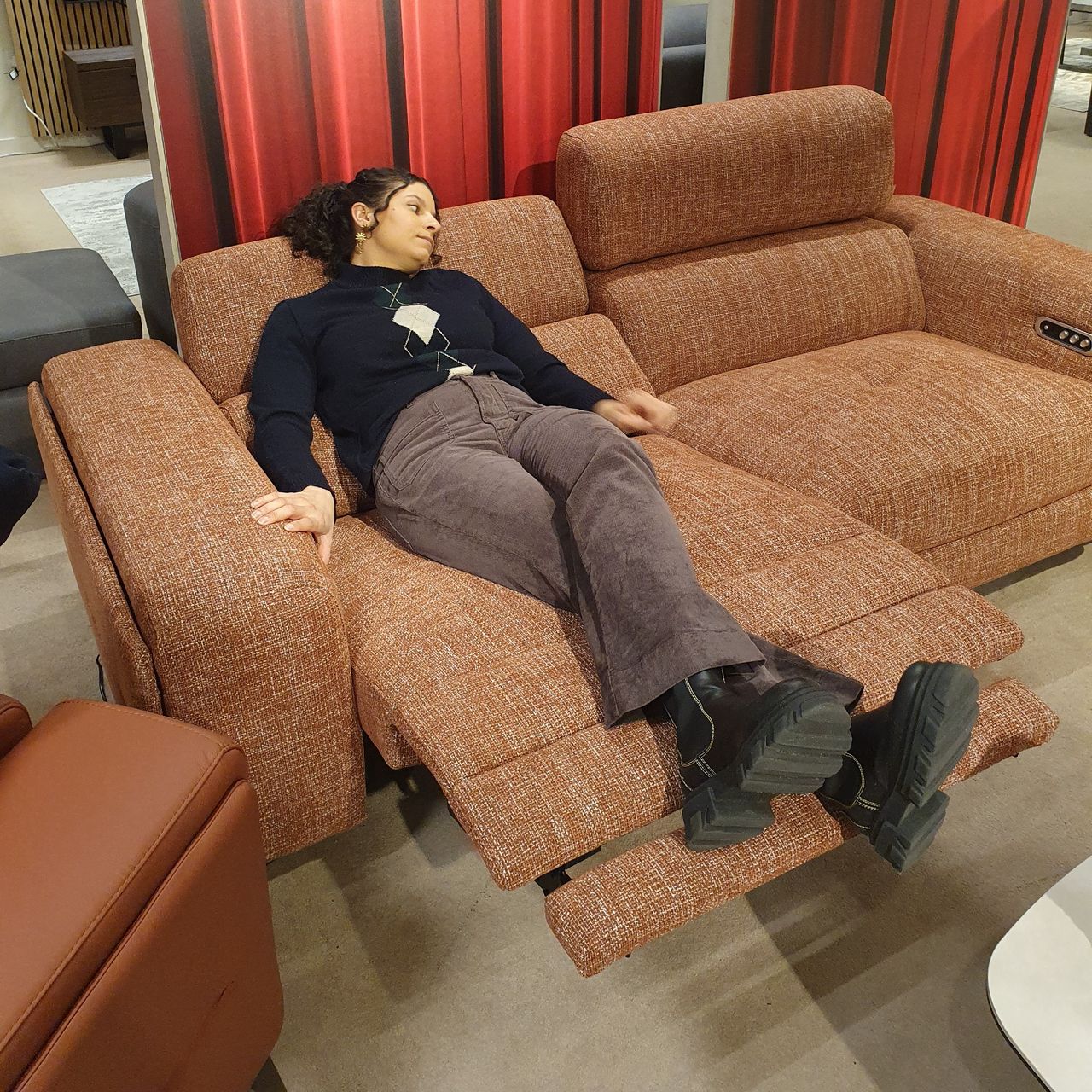Sara lying down on the Furniture Village Action recliner sofa