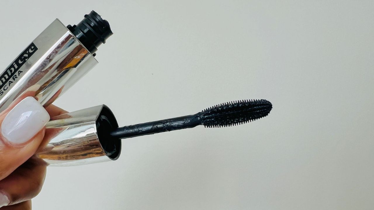 A person holding the L'Oreal Bambi Eye mascara wand and showing its brush, for the best L'Oreal mascara.