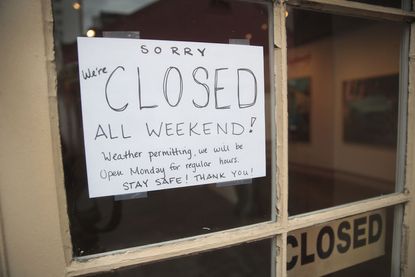A sign saying a shop in New Orleans is closed due to weather conditions.