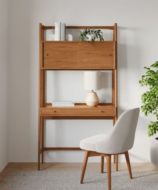 A tall vertical wooden desk with decor on it next to a gray chair