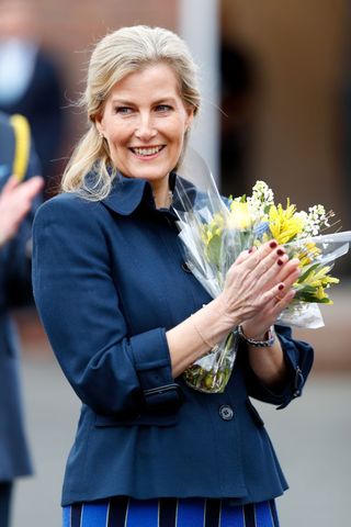 Sophie, Countess of Wessex applauds the crowd, holding a bouquet of flowers, at the opening of the Sir Ken Dodd Happiness Hall