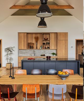 Kitchen with sleek wood cabinets, retro school chairs and industrial lighting