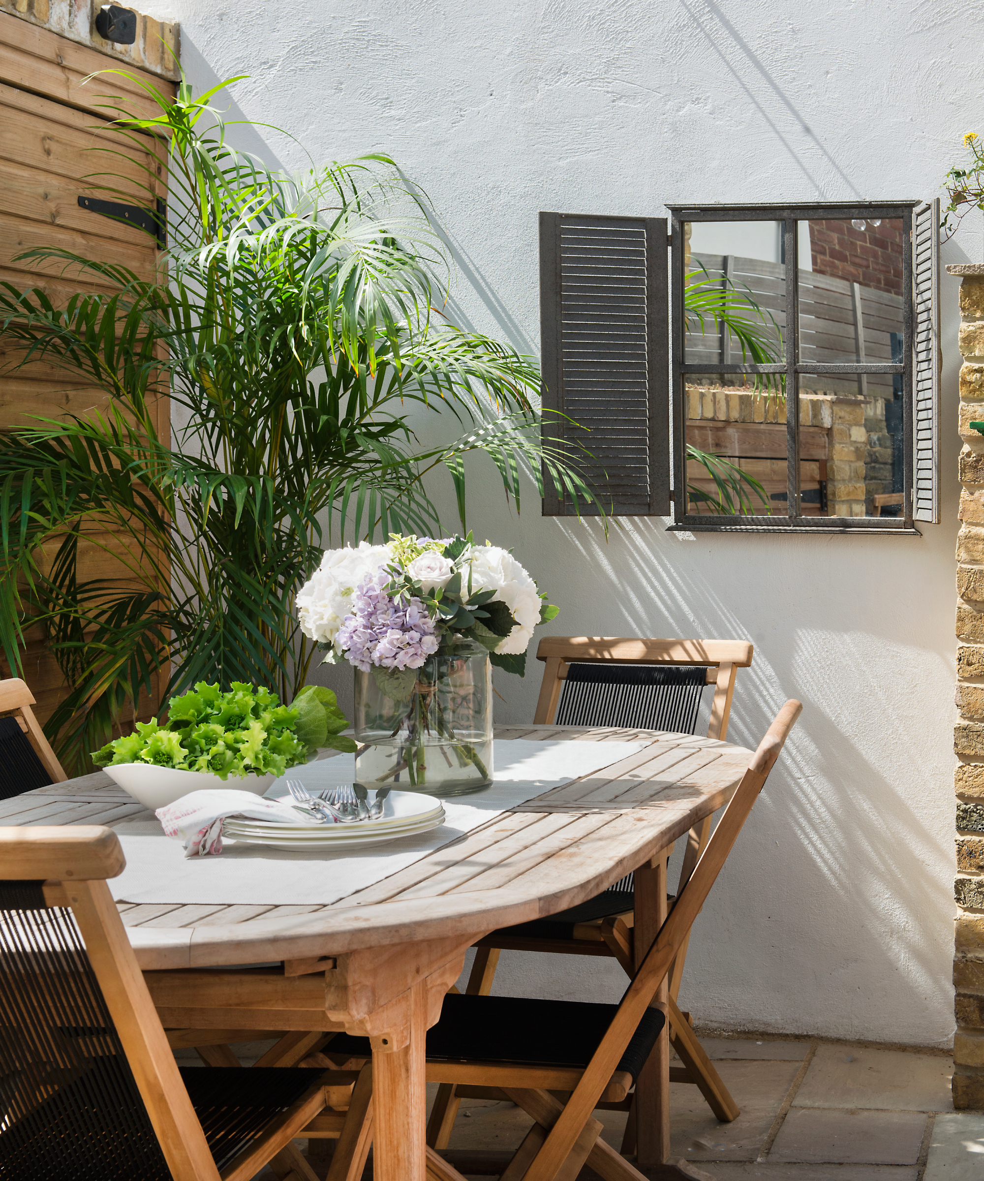 Mirror hung on a garden wall to give the illusion of more space in a small urban garden
