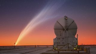 a fuzzy streak of light close to the horizon below a sky full of stars