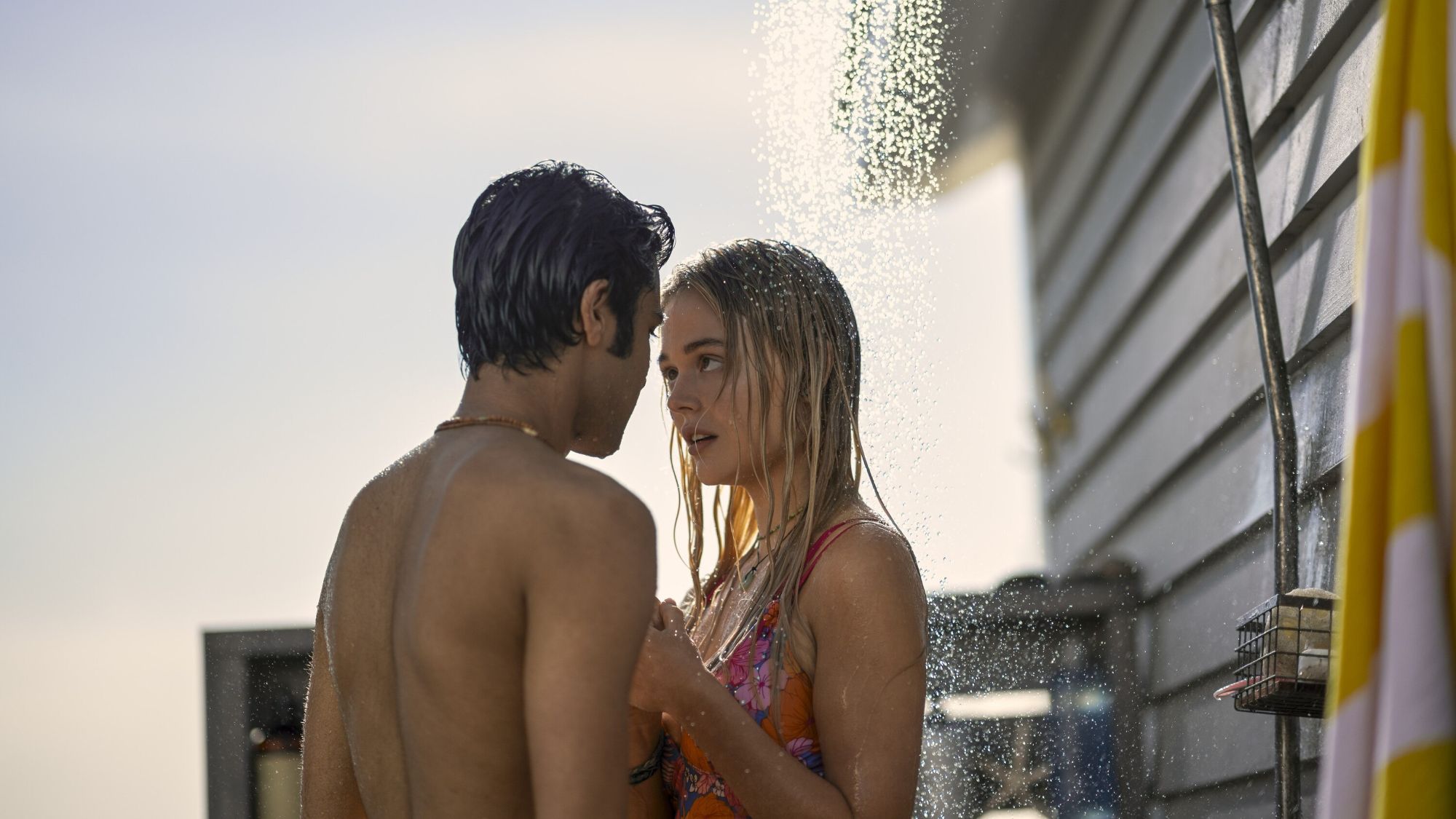 Shubham Maheshwari and Emily Alyn Laid taking an outdoor shower in their swimsuits in We Were Liars