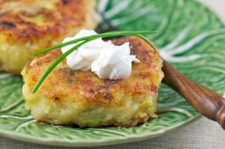 Close up of potato cake on a plate topped with cheese and chive