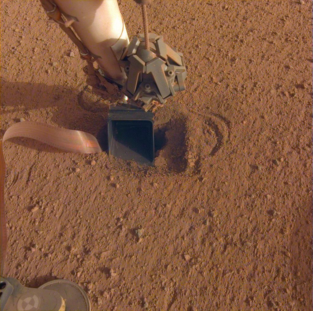 The burrowing heat probe aboard NASA&#039;s InSight Mars lander lies in a shallow pit beneath InSight&#039;s scoop, seen in this photo captured by the lander on June 20, 2020. 