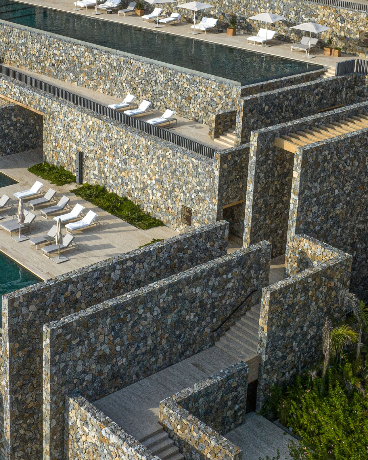 four seasons tamarindo resort shown from an areal view. walls of stone hold layers infinity pools and a maze of stairs.