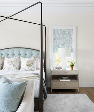 bedroom with white walls four poster frame and blue upholstered bedhead