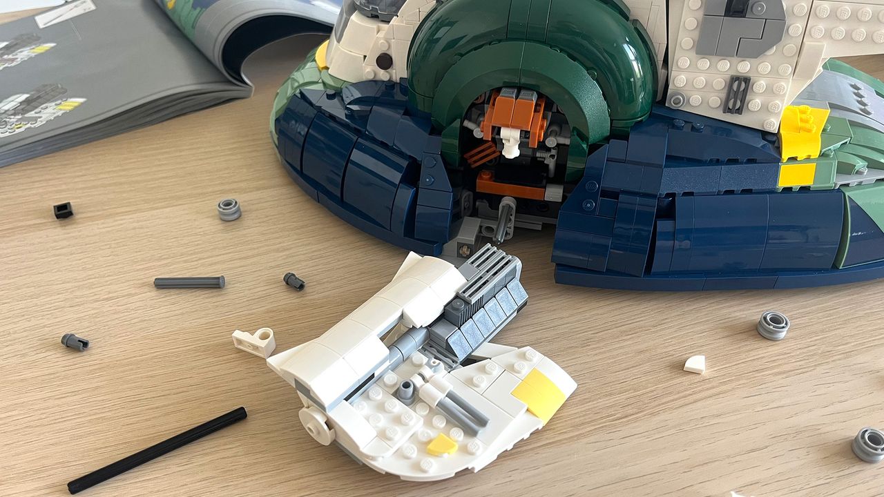Lego Star Wars UCS Jango Fett&rsquo;s Firespray-Class Starship (75409) mid-build on wooden tabletop next to lots of Lego pieces and an instruction booklet