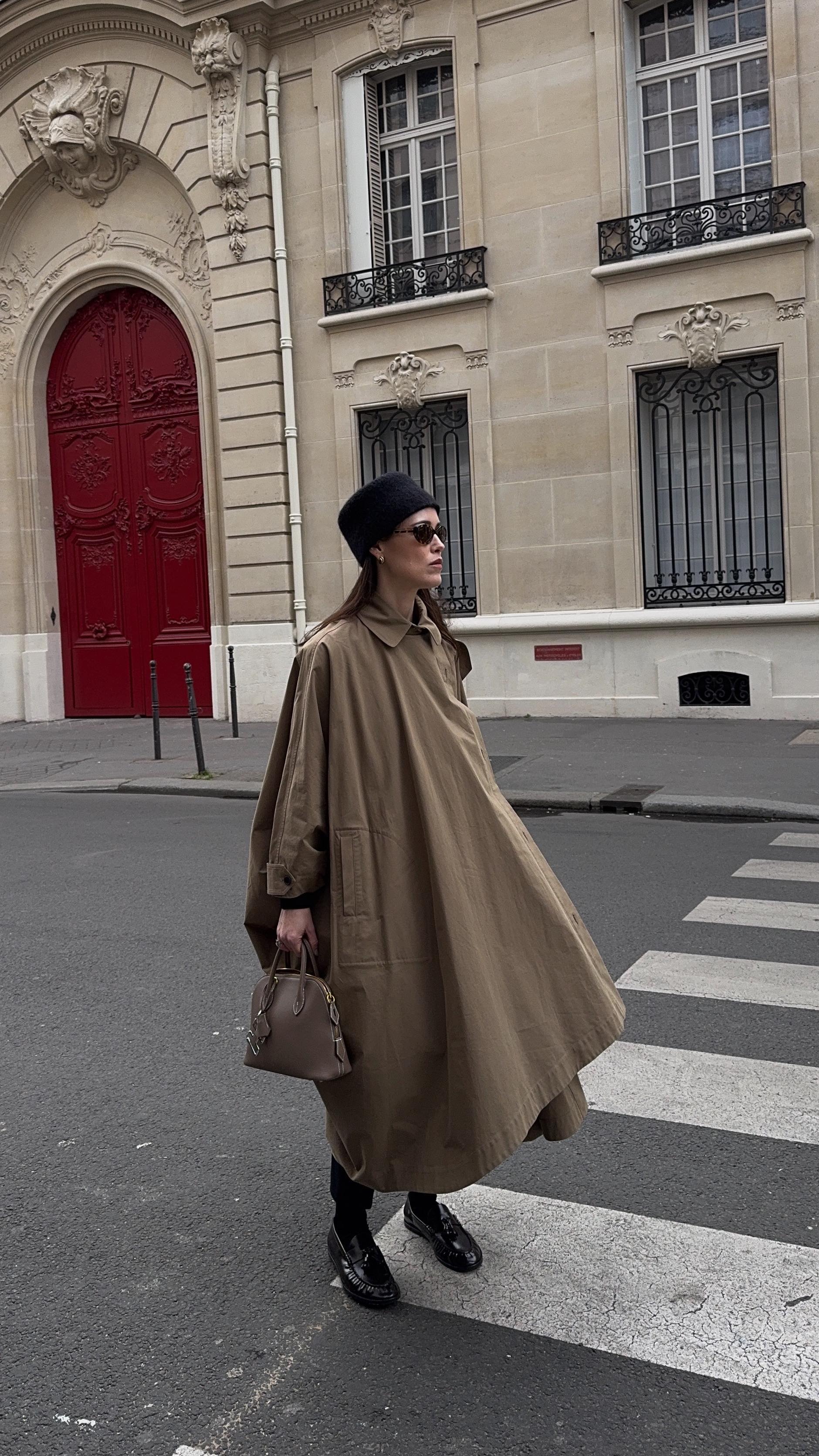 An image of @annabelrosendahl wearing one of the best cape coats with a pair of black patent loafers and a pill box hat.