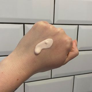 Lucy's hand showing a swatch of Tatcha The Liquid Silk Primer