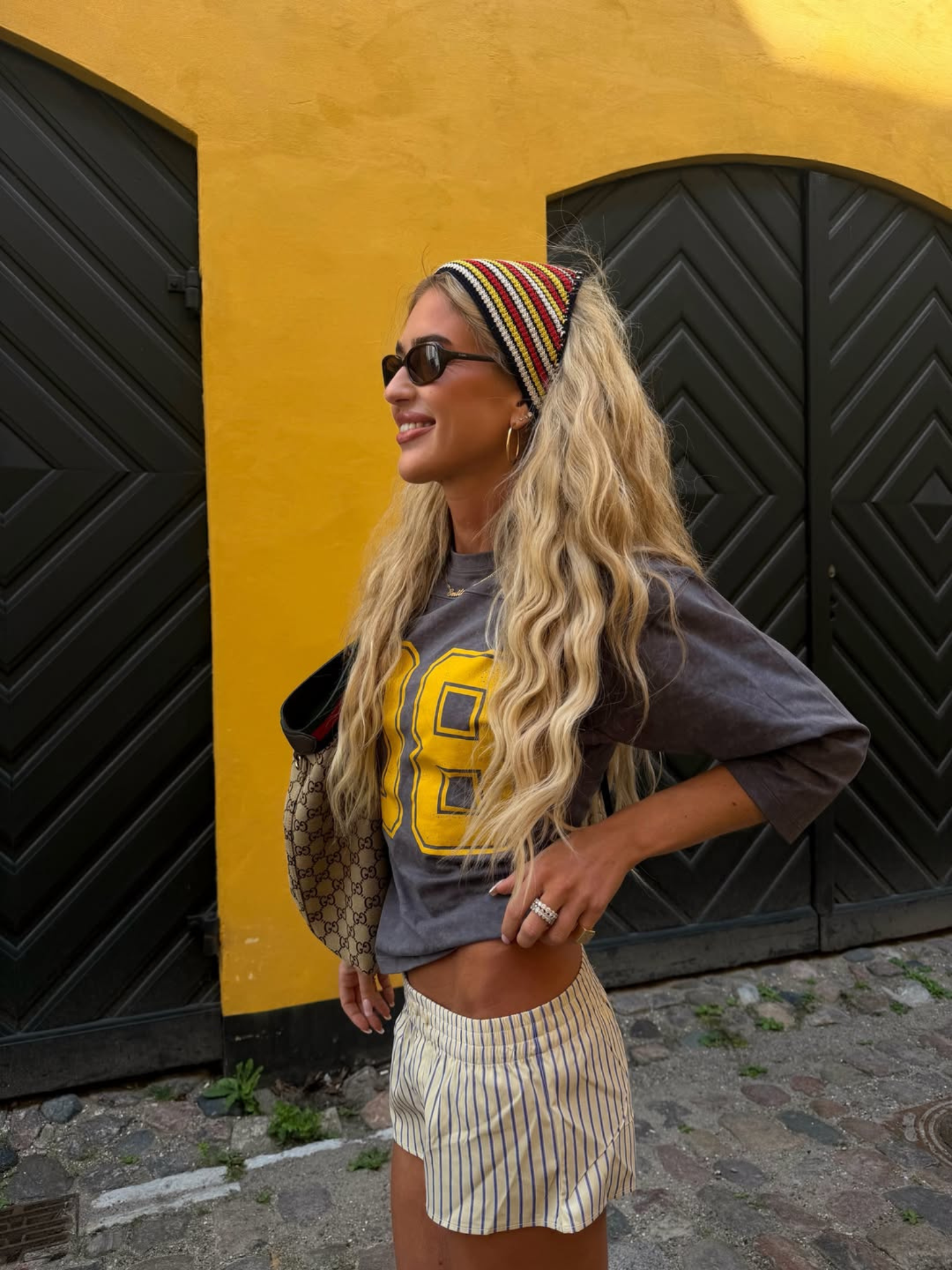A woman with long blonde hair wearing sunglasses and a headscarf