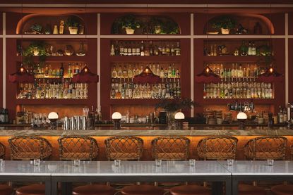 The bar counter of a cosmopolitan chic restaurant mixes glamorous touches with rustic rattan and earthy surfaces.