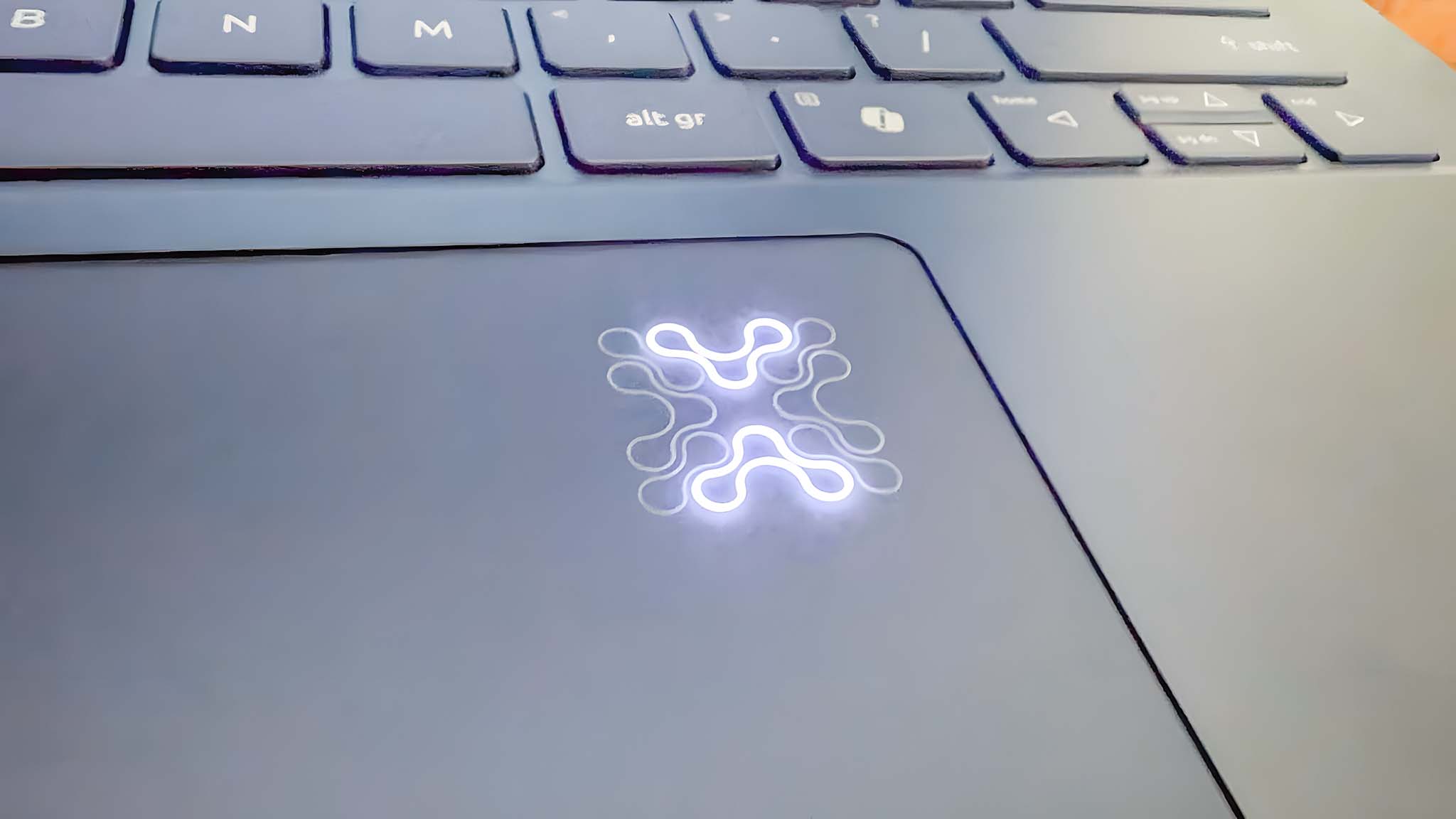 Closeup showing that the symbol on the upper right corner of the touchpad lights up on the Acer Swift 14 AI.