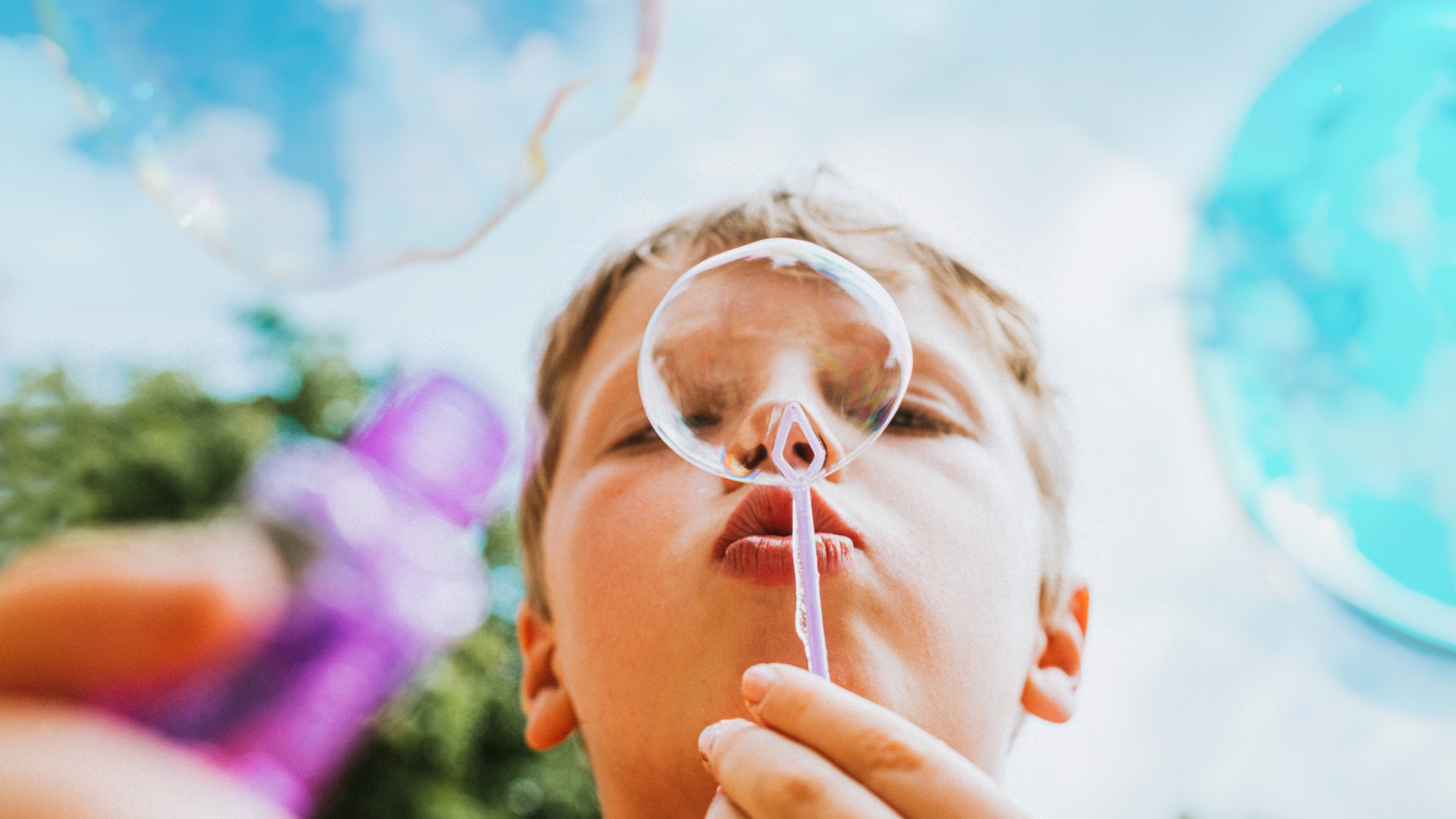 A boy blows through a bubble wand