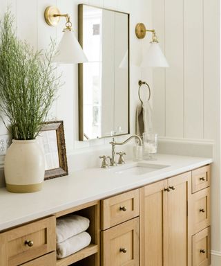 Wood and white bathroom with shiplap walls, white countertop, mirror, wall lights