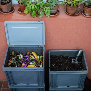 Two plastic compost bins with lid on brick patio