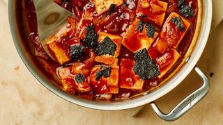 overhead shot of a skillet filled with gochujang-braised tofu that is topped with pieces of nori