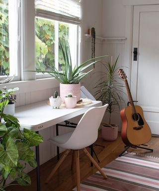 Home office with potted plants and guitar
