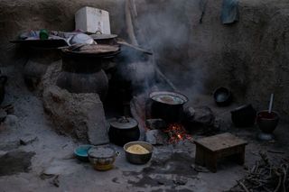 Gando: the exterior kitchen in a communal courtyard in the evening hours as the sun is setting and the fire’s ambers provide the only source of light