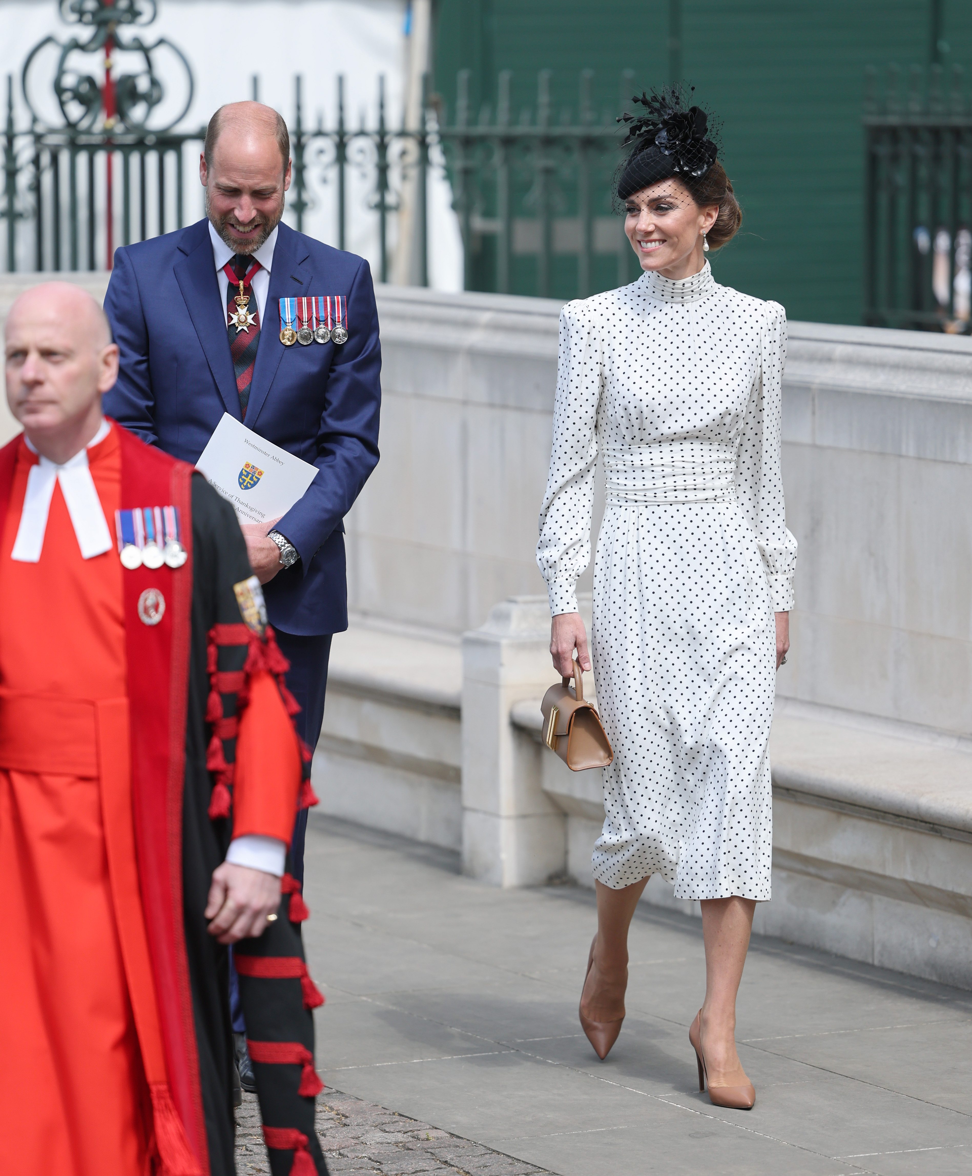 Princess Kate wearing a white polka dot dress walking next to Prince William