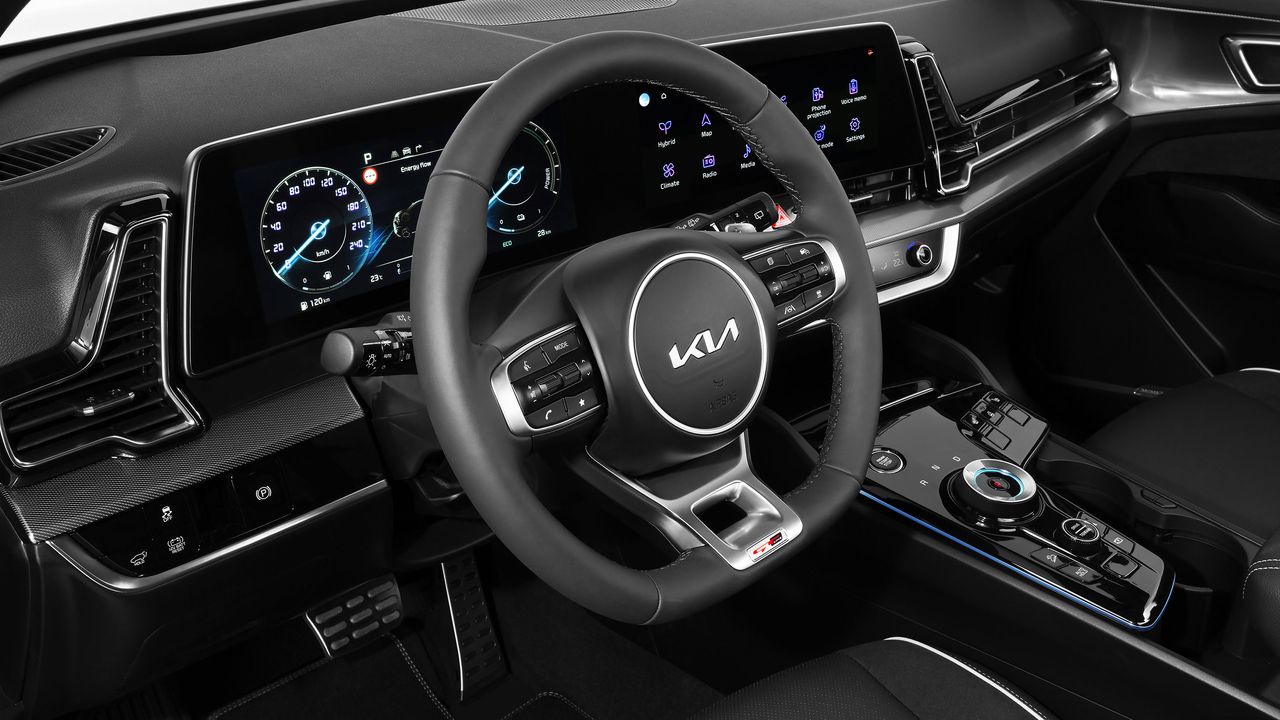 A steering wheel and dual displays inside the cabin of a car