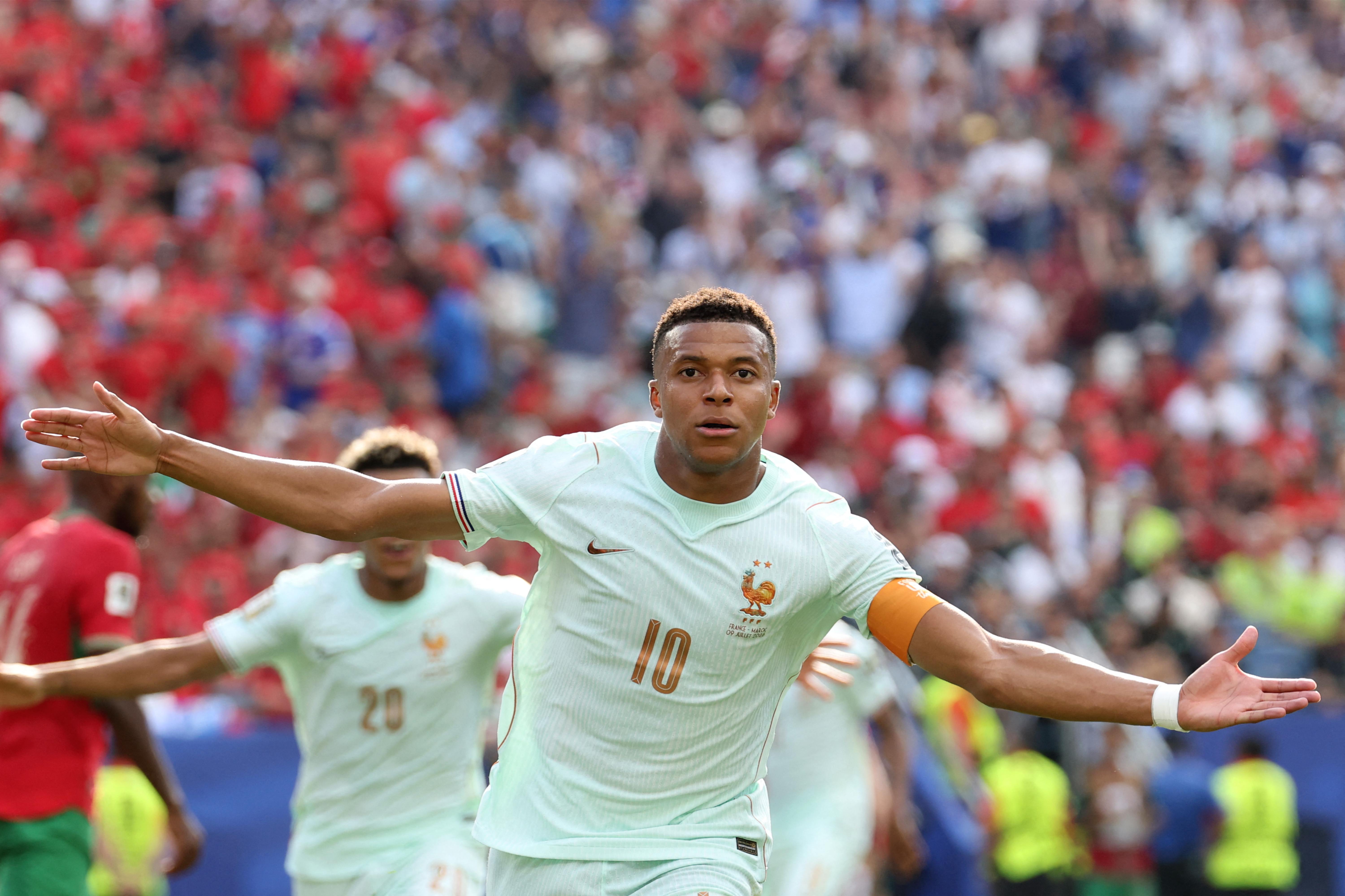 Kylian Mbappe running with his arms out.
