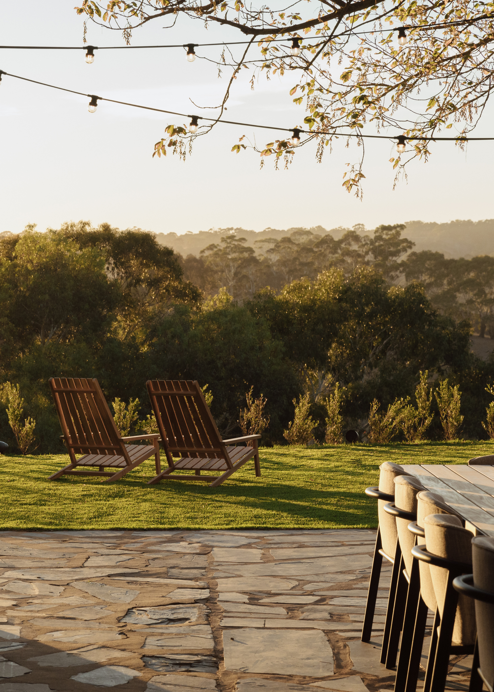A backyard with a pair of wood garden chairs by an al fresco dining table