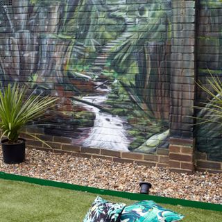 green lawn edged with pebbles against a wall mural