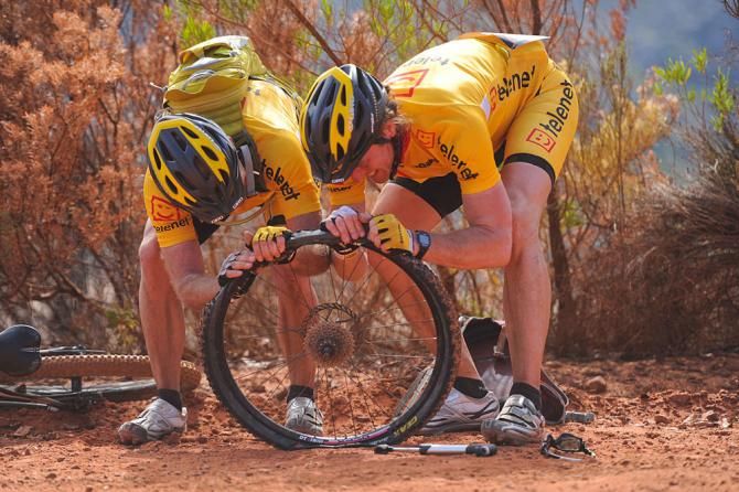 Riders try fix puncture during stage
