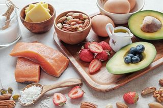 A photo showing lazy keto approved foods like butter, salmon, nuts, strawberries, blueberries and avocado.