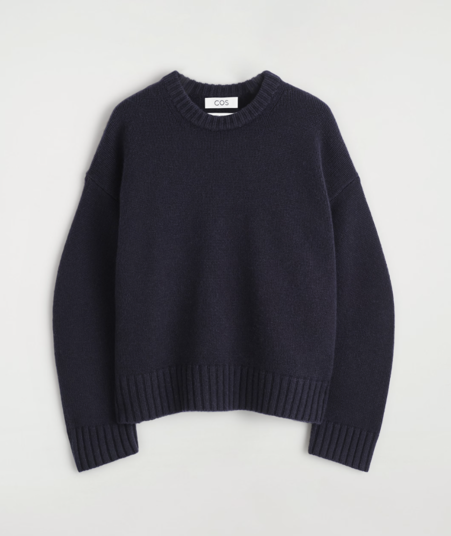 a ribbed cos sweater in front of a plain backdrop