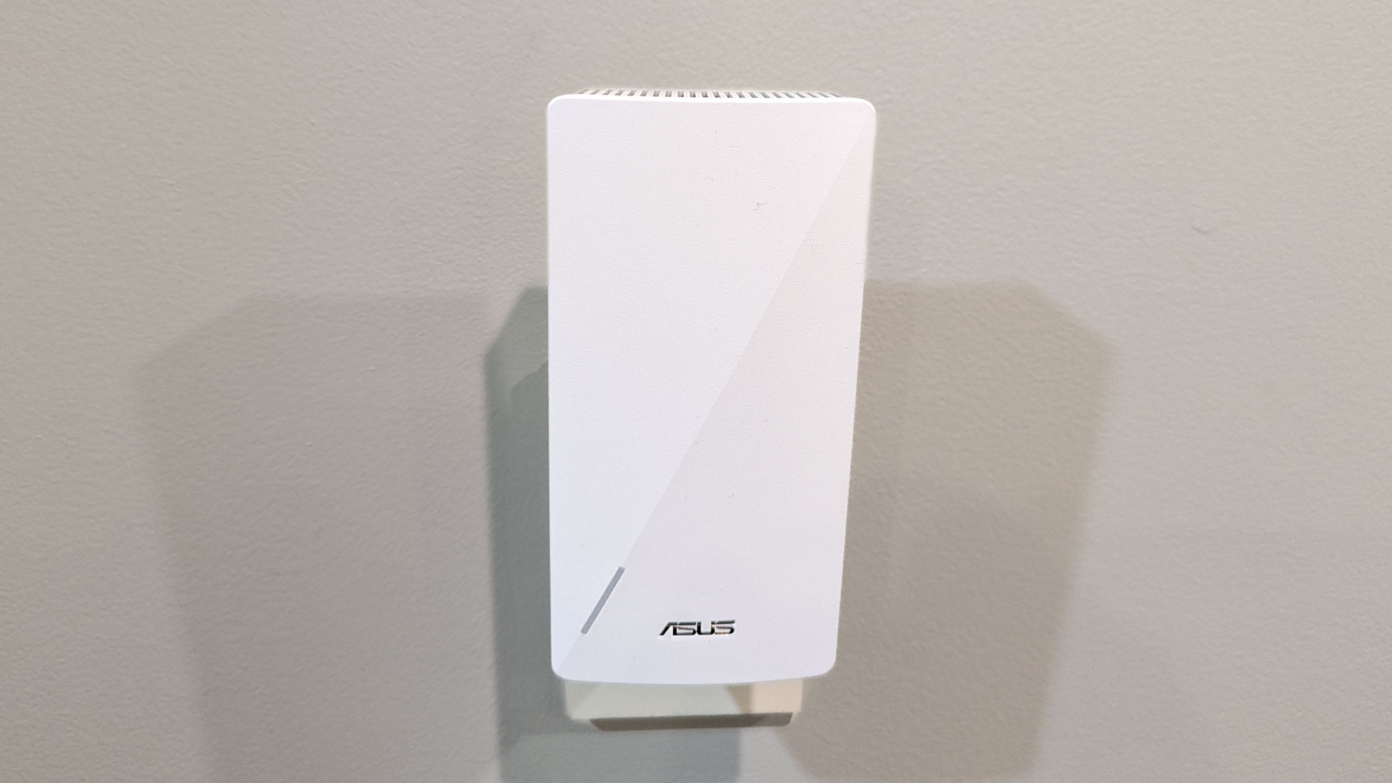 Close up of an Asus RP-AX58 Wi-Fi 6 extender plugged into a wall socket.